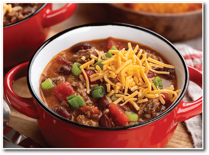 Closeup of bowl of chili con carne with cheddar cheese